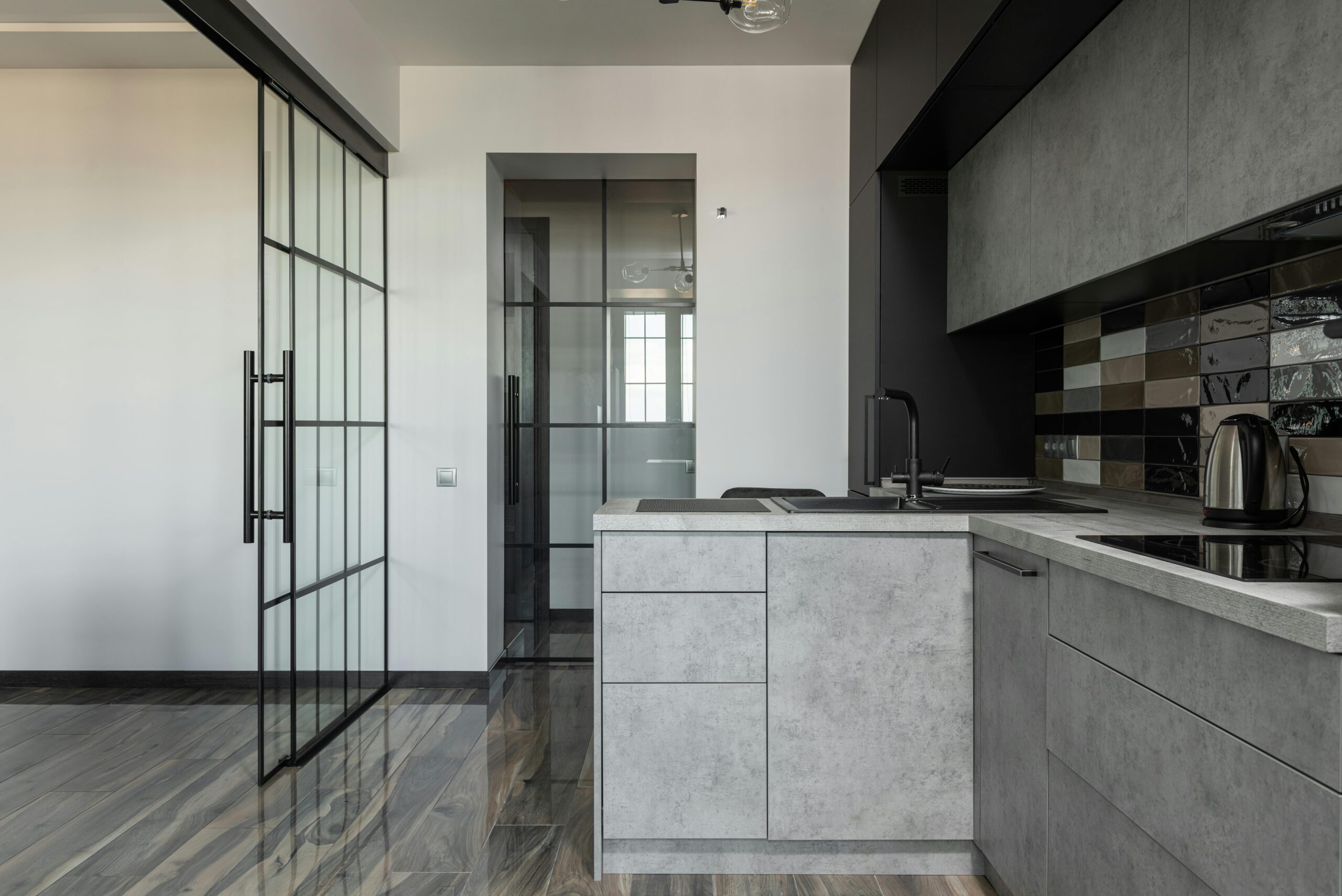 Contemporary kitchen featuring grey cabinets, glass partition, and marble elements.