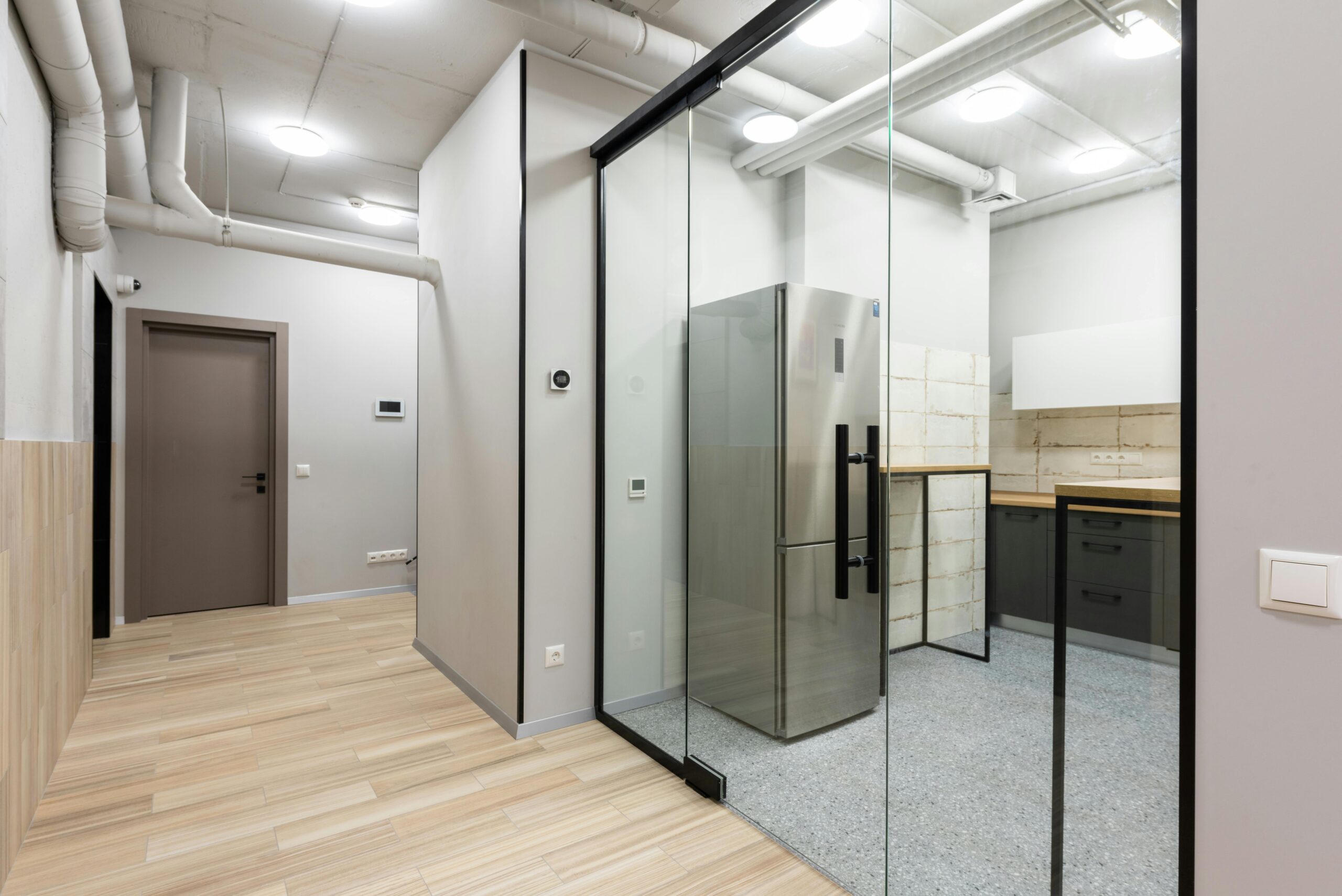 Sleek and contemporary interior showcasing a kitchen area with glass partition and modern appliances.